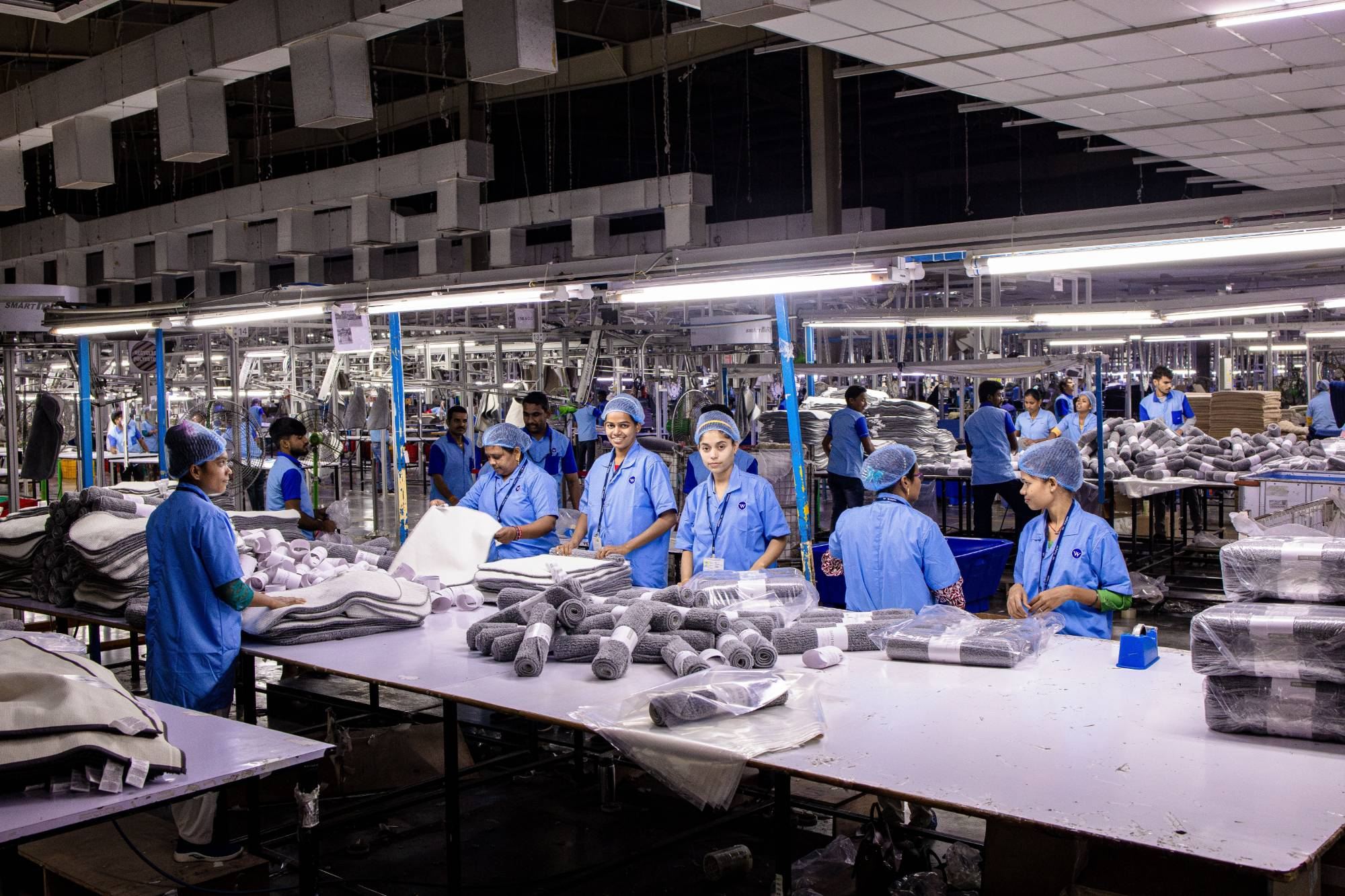 Factory production floor with workers packing textile goods